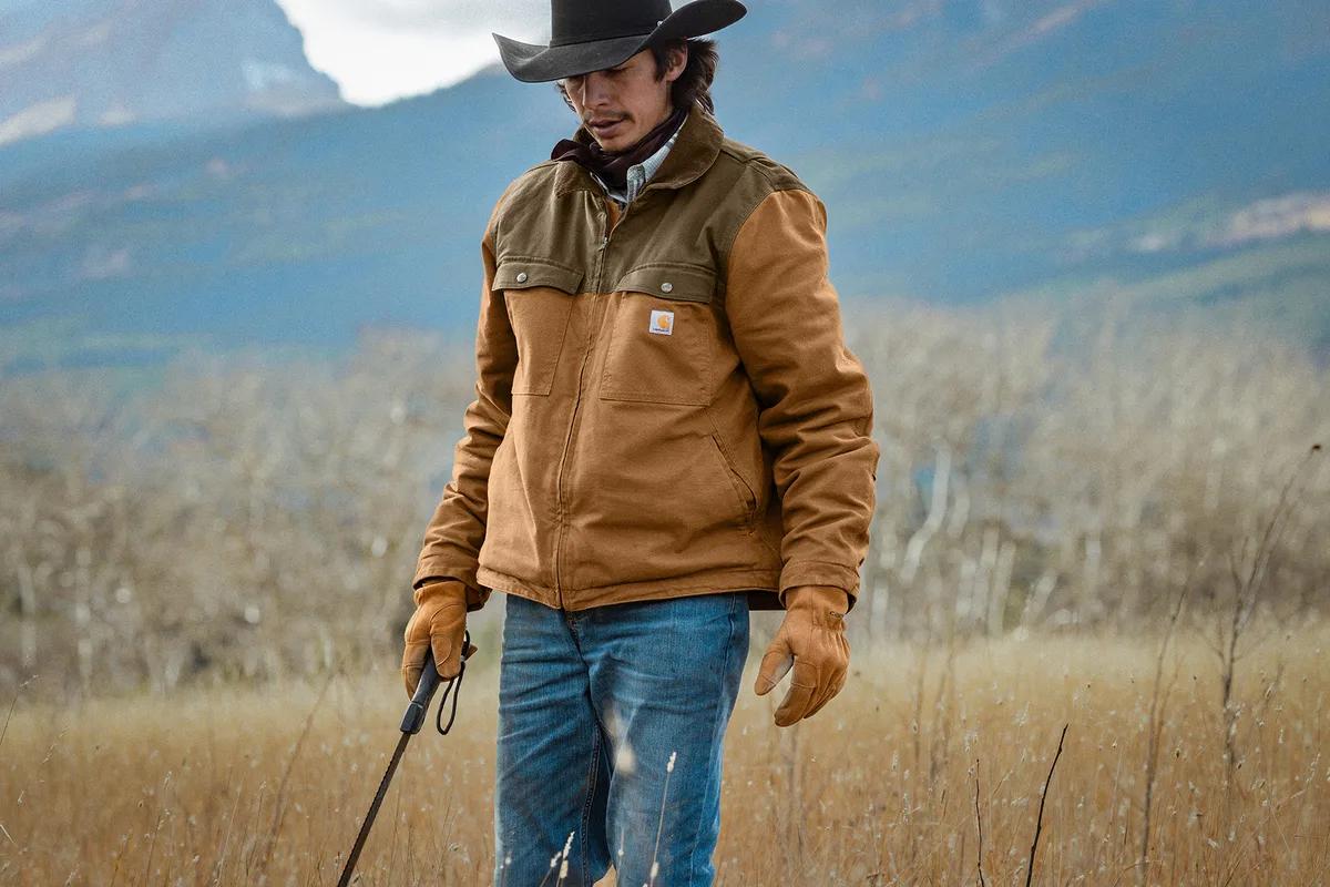 Rancher wearing a Carhartt Montana duck jacket in a mountain pasture