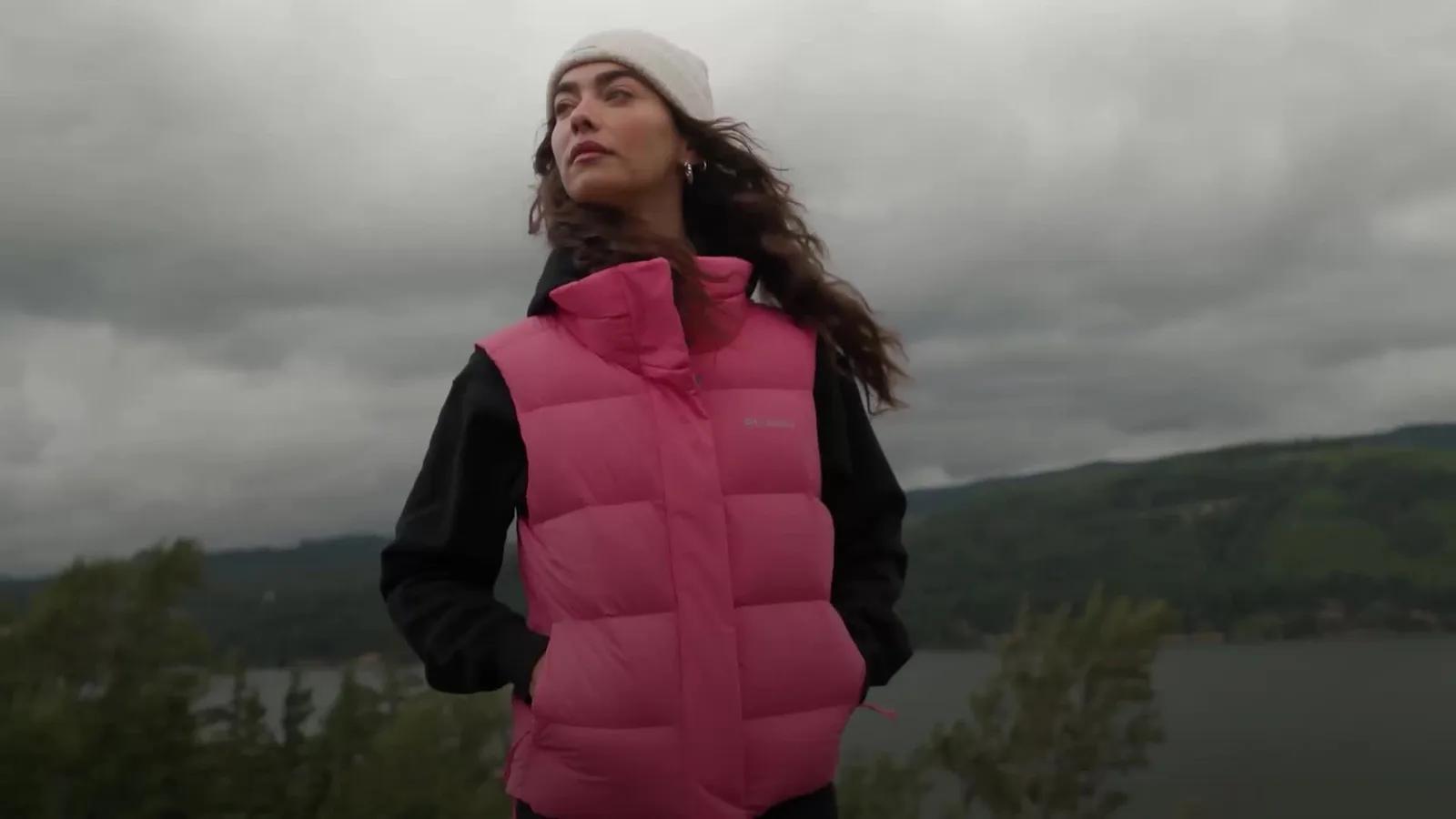 Woman in a pink Columbia puffer vest above a river gorge