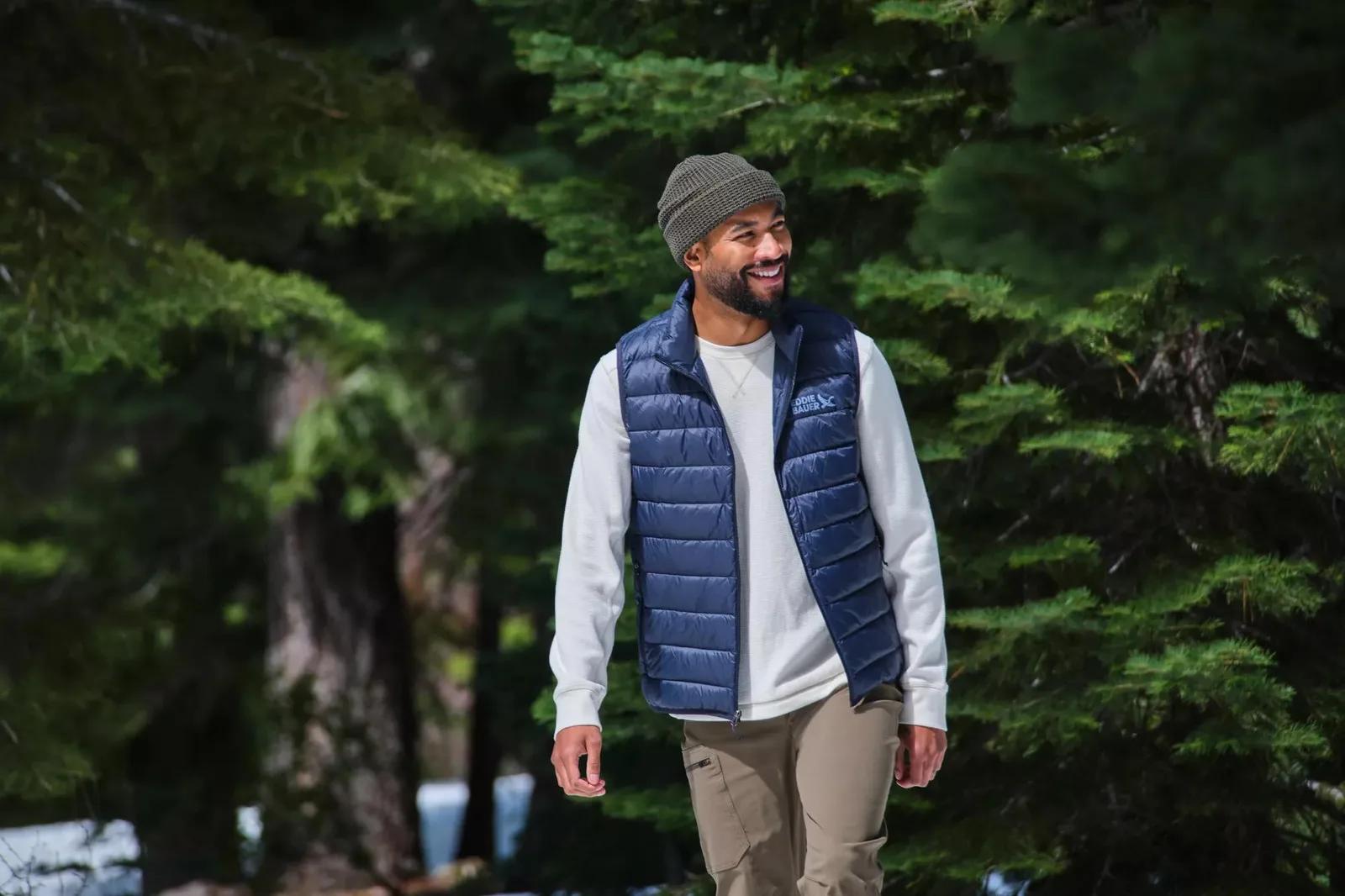 Man in an Eddie Bauer down vest walking through a snowy forest