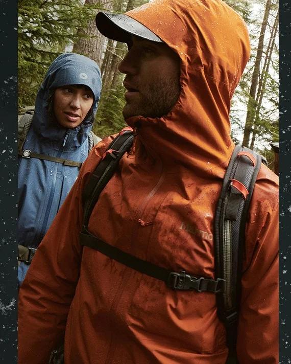 Two hikers in Marmot rain jackets on a forest trail