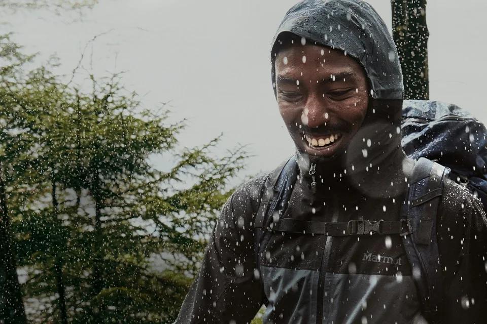 Hiker smiling in the rain in a Marmot waterproof shell jacket