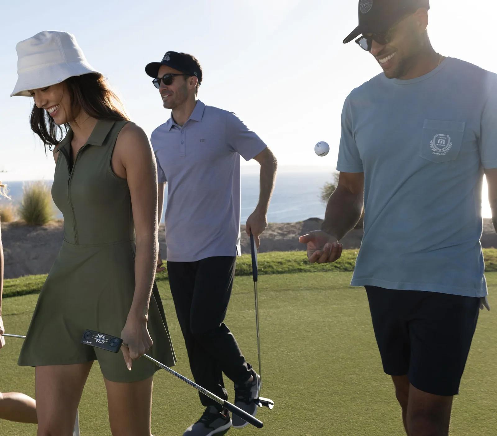 Three golfers in TravisMathew polos walking a fairway