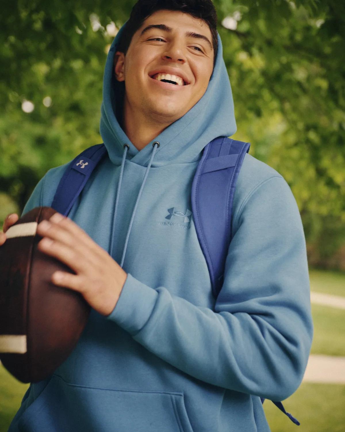 Teen in an Under Armour Icon fleece hoodie holding a football