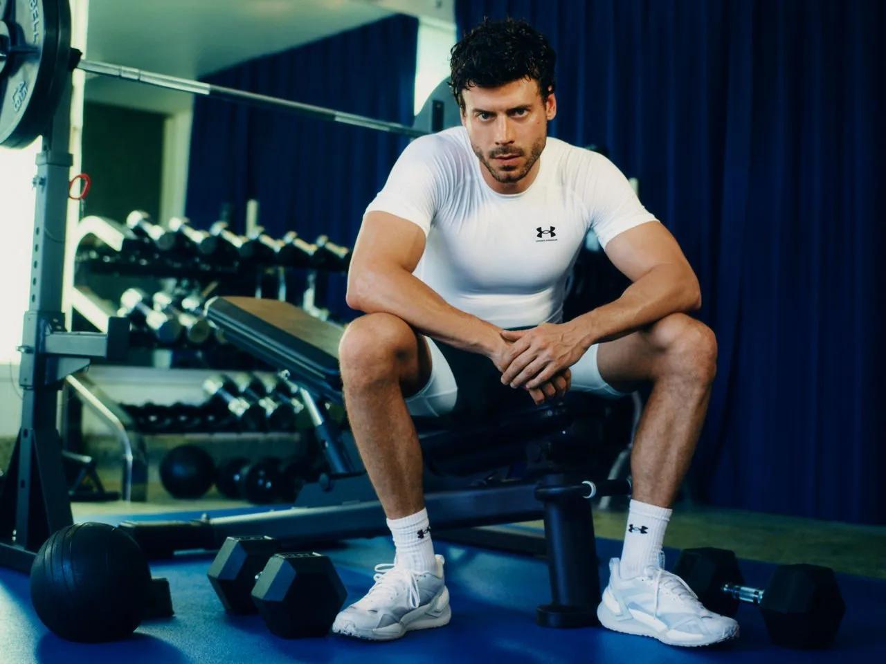 Athlete in an Under Armour tee resting on a gym bench